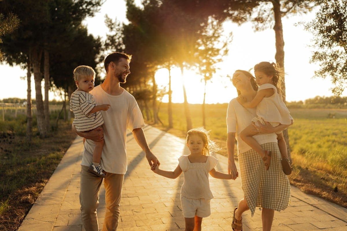 A family walking hand in hand down a sunlit path